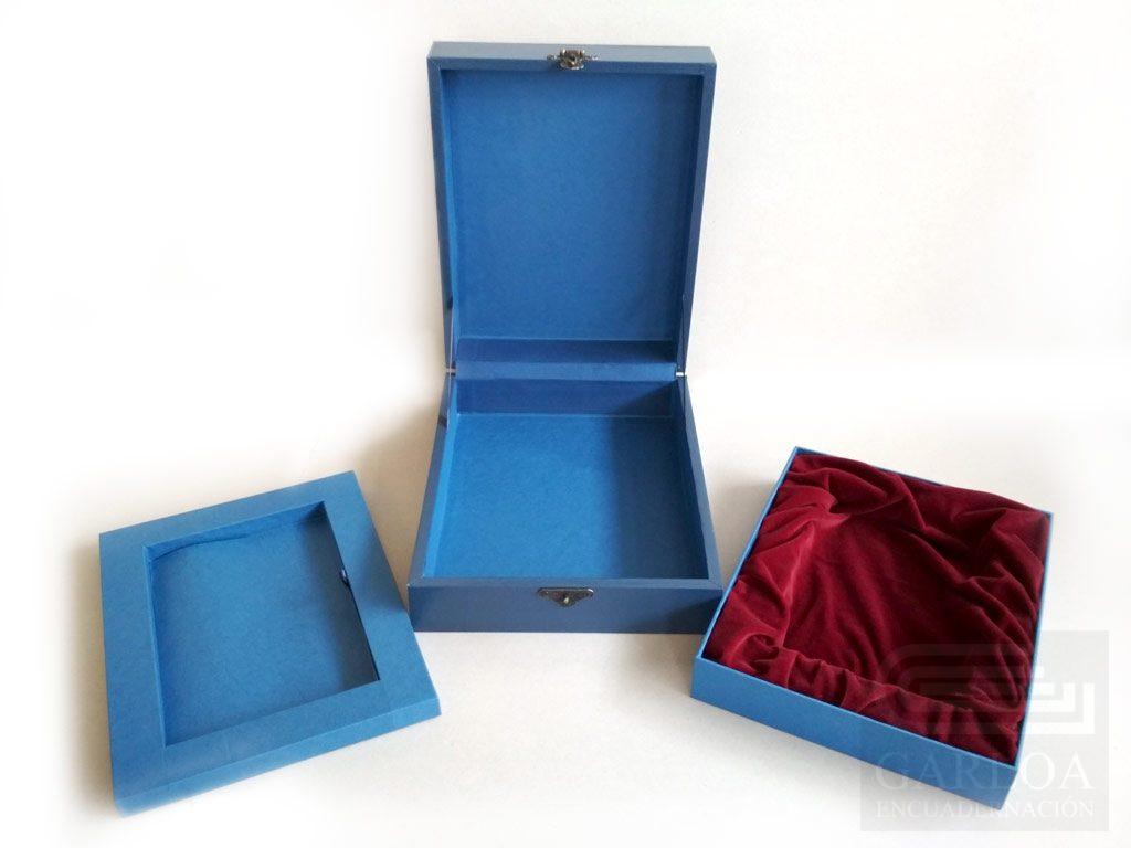 Caja de madera con cierre de metal y orlas y sello metálico en la tapa, con dos cajetines.